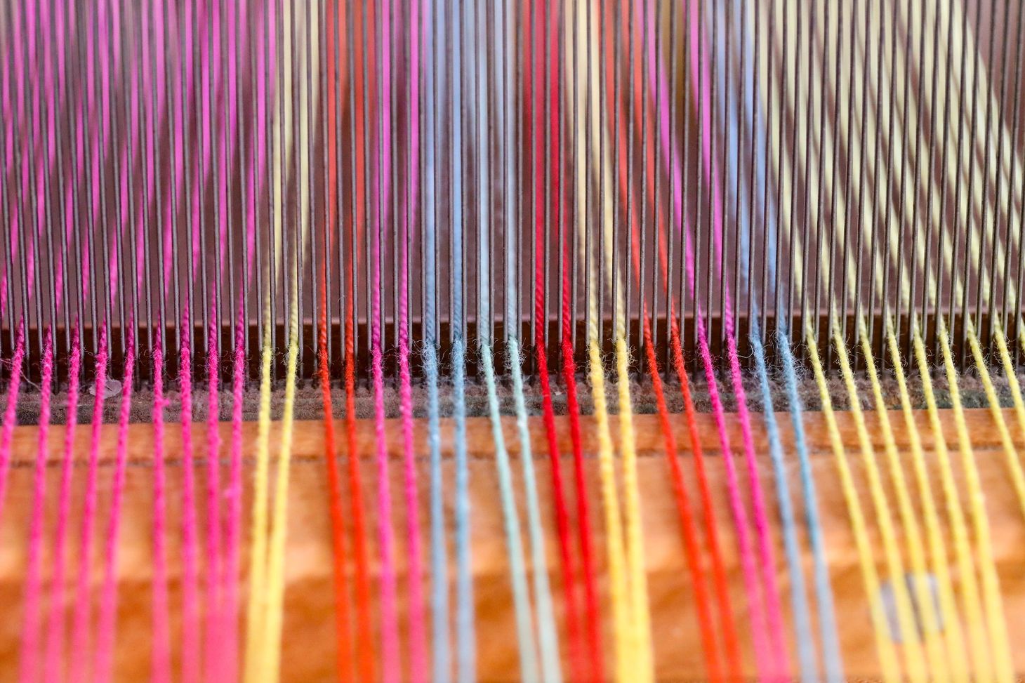 Multi-colored threads being fed into a loom for weaving